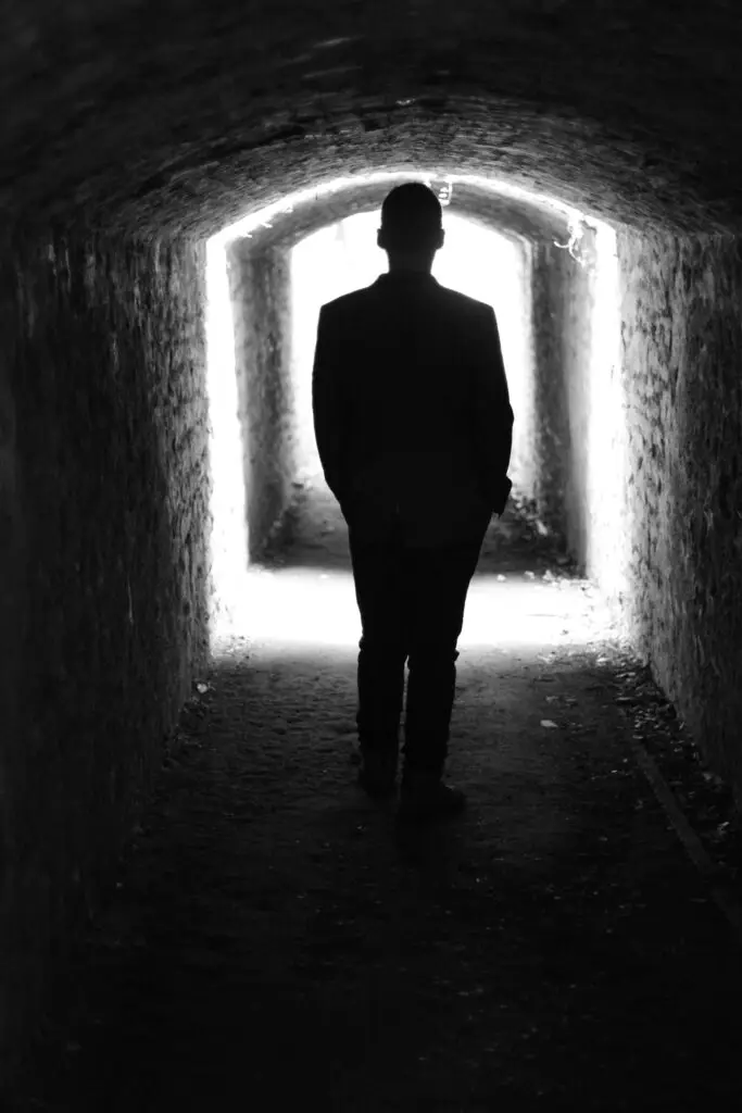 Silhouette of man in a tunnel with light at the end