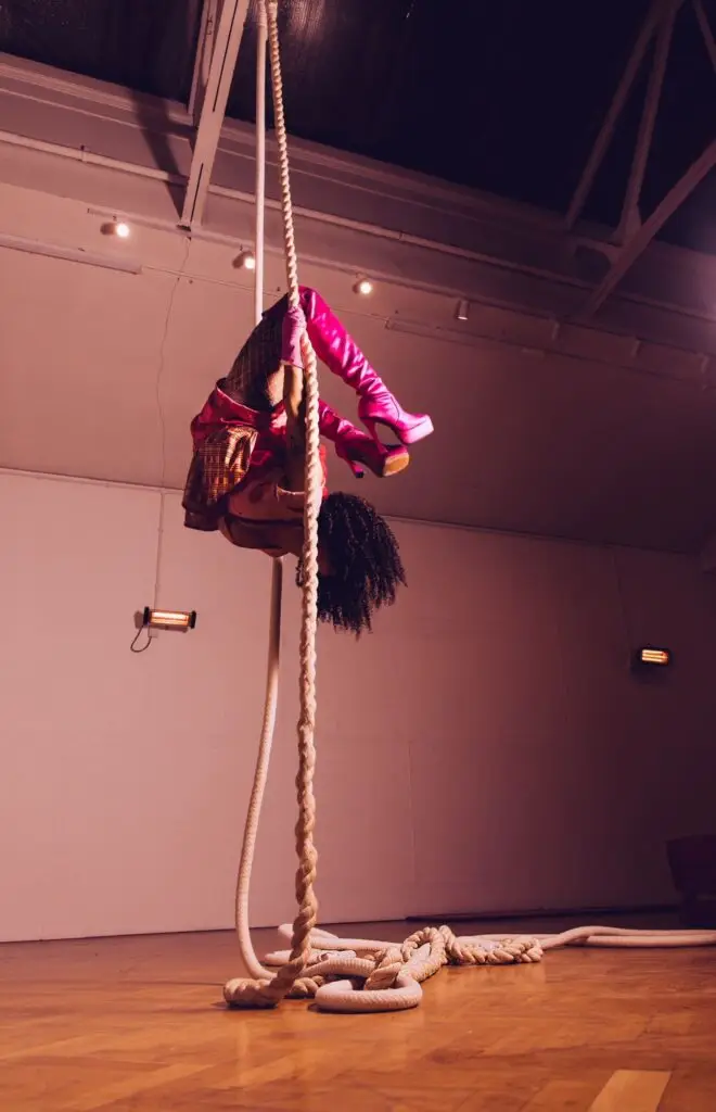 Mariela Gedge hanging upside down in an acrobatic pose holding on to ropes
