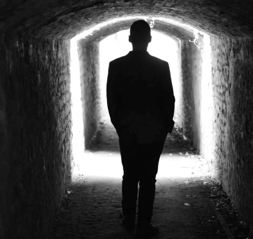 Silhouette of man in a tunnel with light at the end